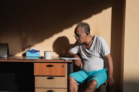 Relaxed asian old man sitting side a tableの写真素材