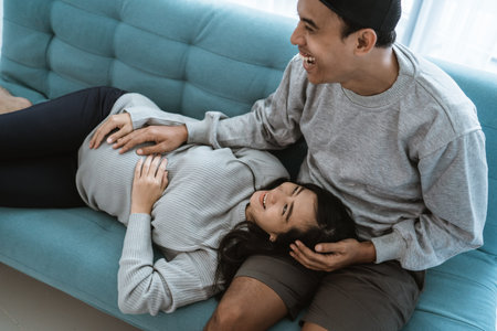 a pregnant wife lies on her husbands lap while relaxing