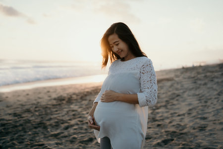 beautiful pregnant woman standing on the beach