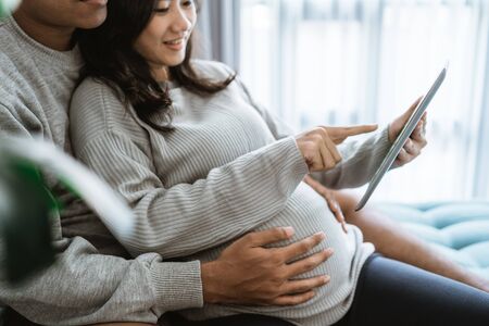 husband and wife use tabs to view pregnancy informationの写真素材