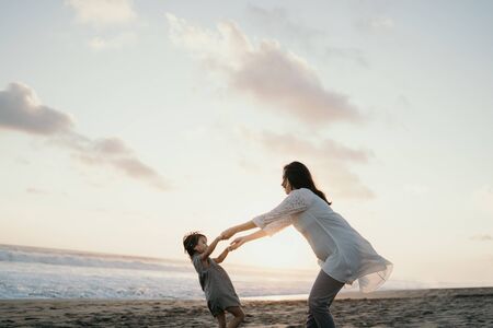 Young mother playing with her little girl by the seaの写真素材