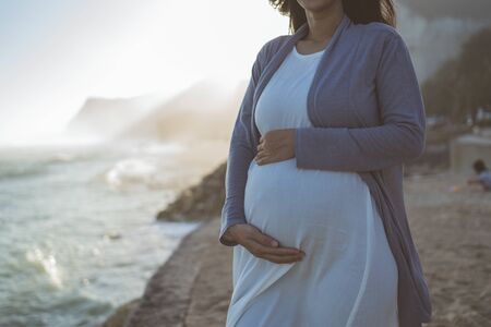 beautiful pregnant woman standing on the beachの写真素材