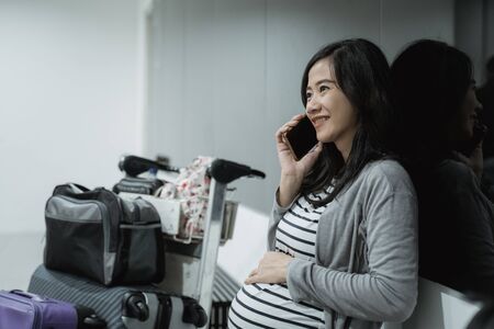 Pregnant woman use cellphones for calling before departureの写真素材