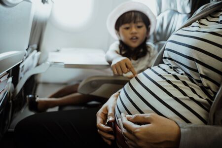 asian little girl enjoy chatting with her mother in the aircraft cabinの写真素材