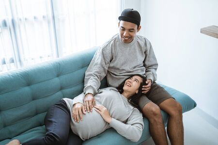 a pregnant woman lay on her husbands lap while sitting relaxedの写真素材