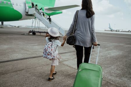 a mother and daughter join hands walking with a suitcaseの写真素材