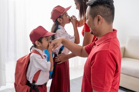 student kiss his parents hand before going to school