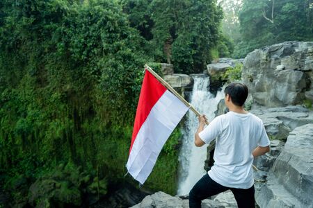 man with indonesian flag of indonesia on top of the mountainの写真素材