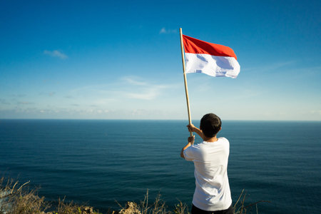 man with indonesian flag of indonesia on top of the mountain