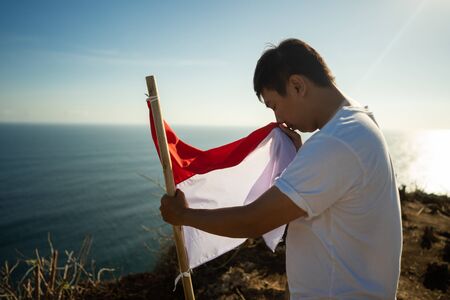 man with indonesian flag of indonesia on top of the mountainの写真素材