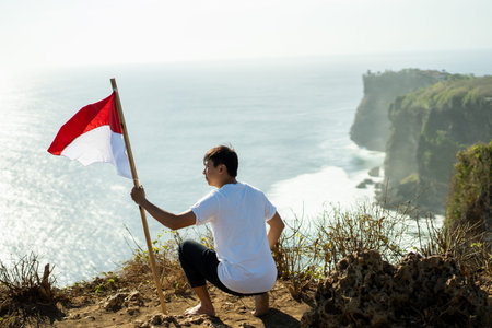 man with indonesian flag of indonesia on top of the mountainの写真素材