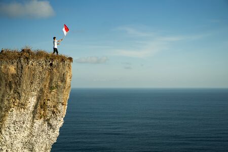 man with indonesian flag of indonesia on top of the mountainの写真素材
