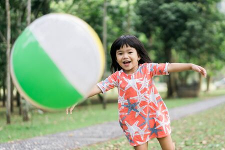 little girl playing baloon ball in the parkの写真素材