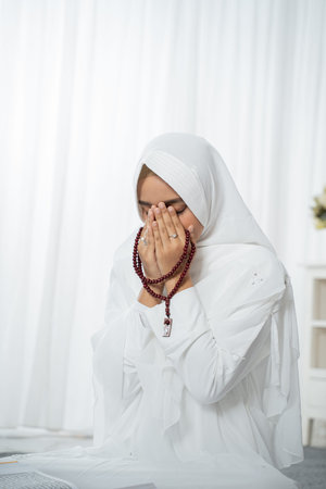 Muslim young woman praying in white traditional clothes