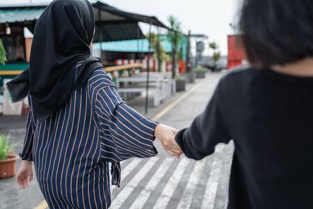 back view of two friends walking togetherの写真素材