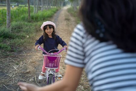 Parent help kid to ride bicycle outdoorの写真素材
