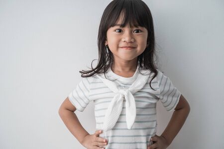 asian little girl smiling with hands on waistの写真素材