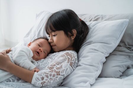 sister with her infant newborn baby sibling play togetherの写真素材