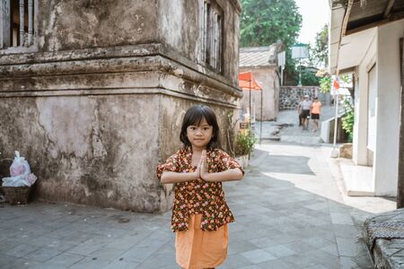 Happy little girl greeting in traditional way from indonesiaの写真素材