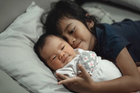 older sister playing with little sister on the bedの写真素材