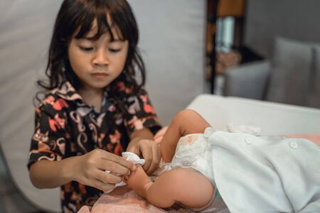 Cute sister helping mother change diaper of his newborn babyの写真素材