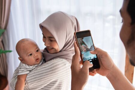 dad take picture of his wife carrying baby boyの写真素材