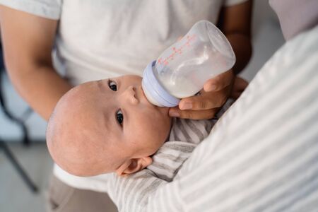 parent feeding baby with bottle of milkの写真素材