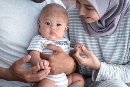 baby boy smiling while sitting on parents lapの写真素材