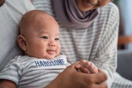 baby boy smiling while sitting on parents lapの写真素材