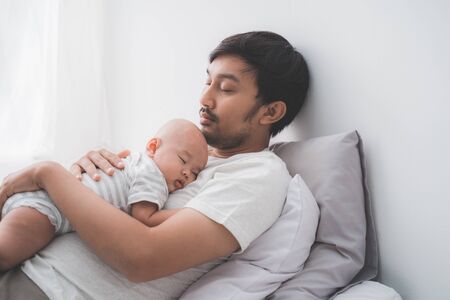 cute baby boy sleeping on fathers chestの写真素材