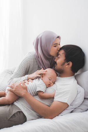 muslim parent kissing together with baby boyの写真素材