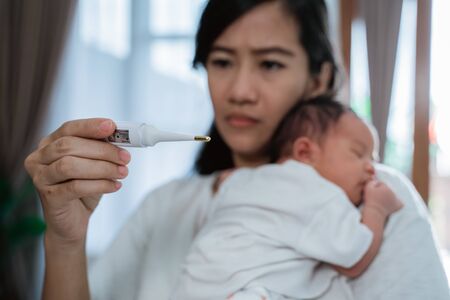 asian mother using thermometer feel worried about their childrens healthの写真素材