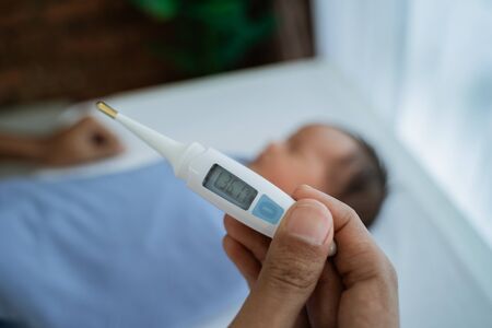 Father measuring temperature to her little babyの写真素材