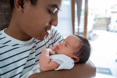 Asian father embrace carrying newborn little daughterの写真素材
