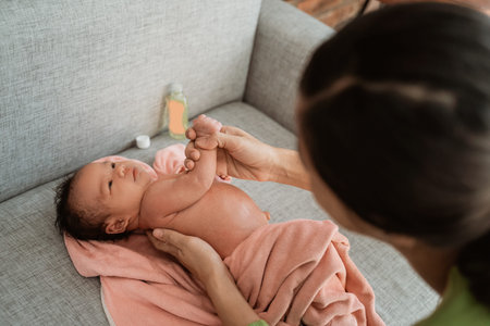 Mother rubs her little girl using oilの写真素材