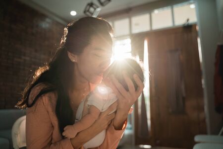 Asian mother kissing her little daughterの写真素材