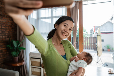 Asian woman take selfie when holding little daughter