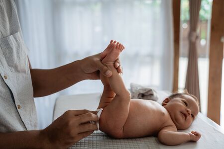 Father rubbing baby buttocks using wet tissueの写真素材