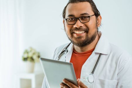 doctor using tablet pc in his office and smilingの写真素材