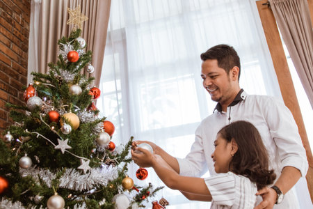 asian dad and girl decorating christmas tree