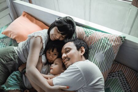 Happy family playing together on the bedの写真素材
