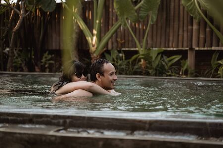 Happy couple hugging in a swimming poolの写真素材