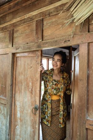 beautiful woman wearing a kebaya opens the doorの写真素材
