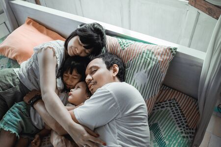 Asian happy family and child daughter relaxing on the bed enjoy holidayの写真素材