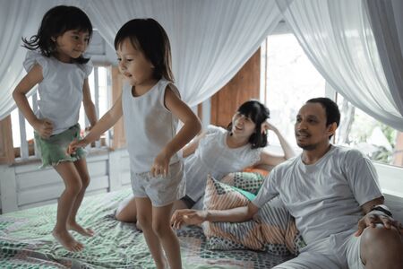 Happy family playing together on the bedの写真素材