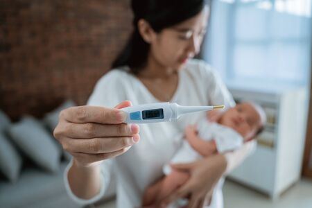 Mother with baby newborn and thermometerの写真素材