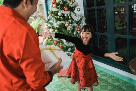 Father giving her daughter a present on christmas dayの写真素材