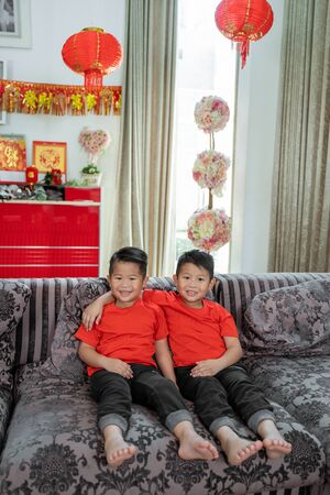 two asian boys smile wearing red shirtsの写真素材