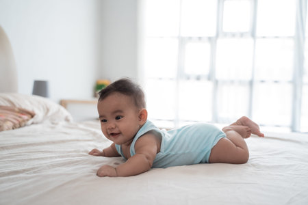 baby lying on belly playing on the bed