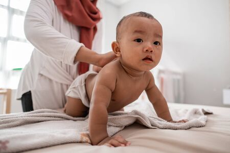 mother applying baby oil to her babyの写真素材